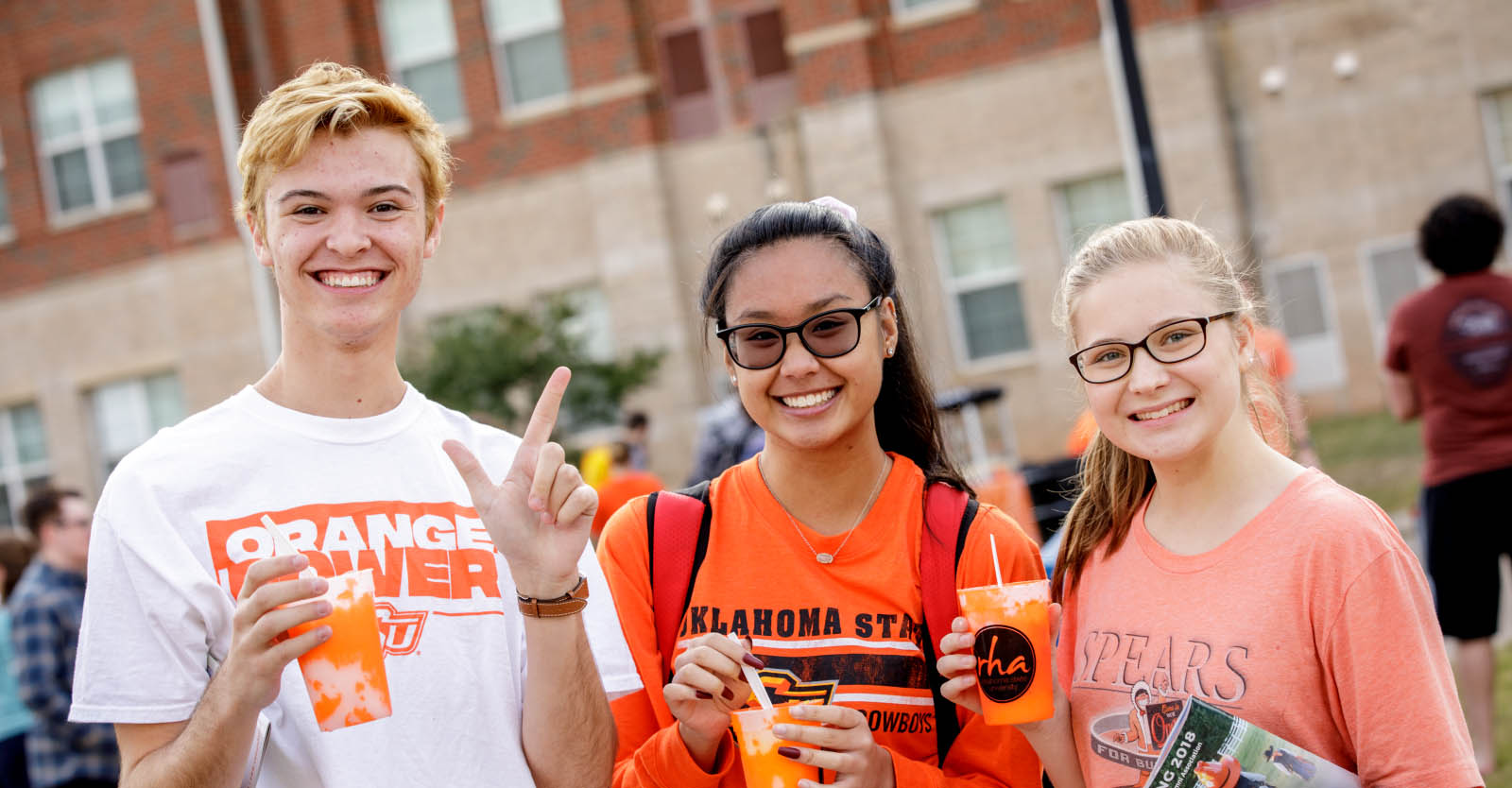 Three students smile outside a residence hall on OSU's campus.