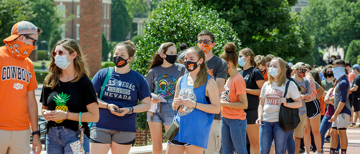 Masked students stand in an outdoor line on OSU's campus.