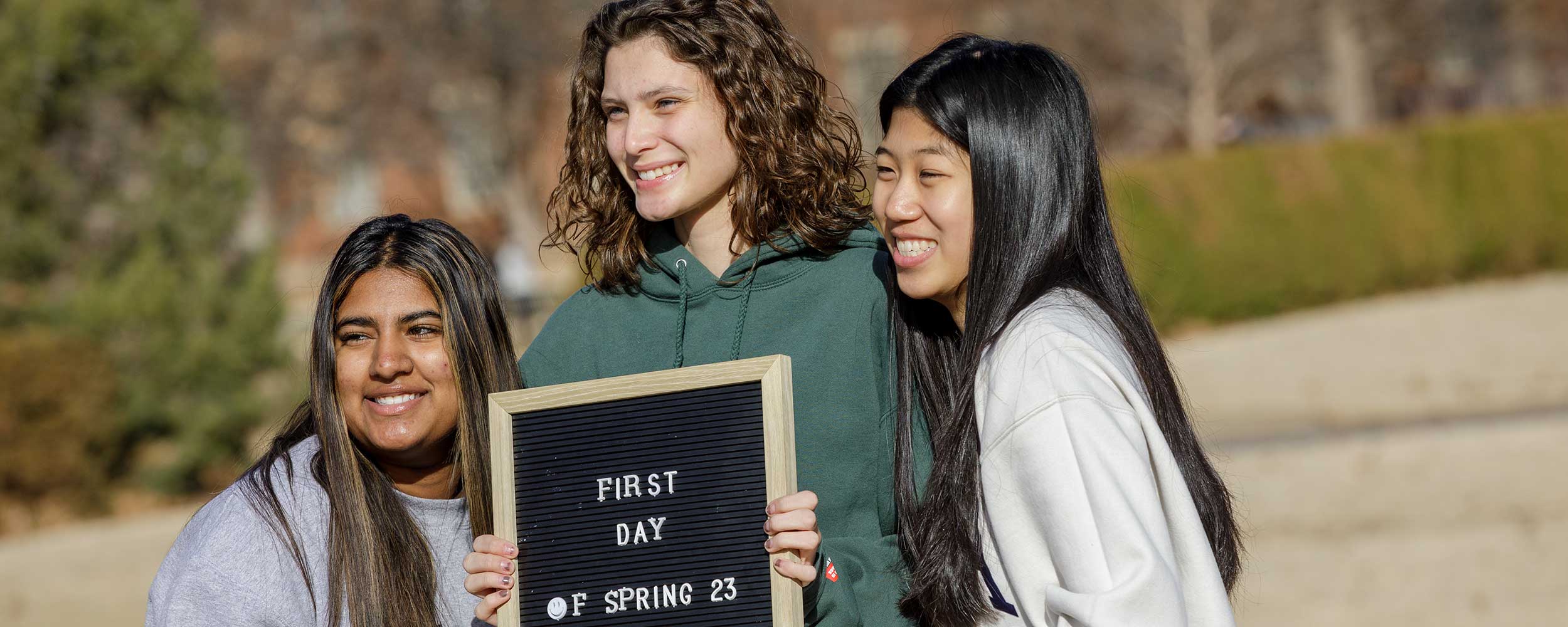 Three students holding a sign that says 